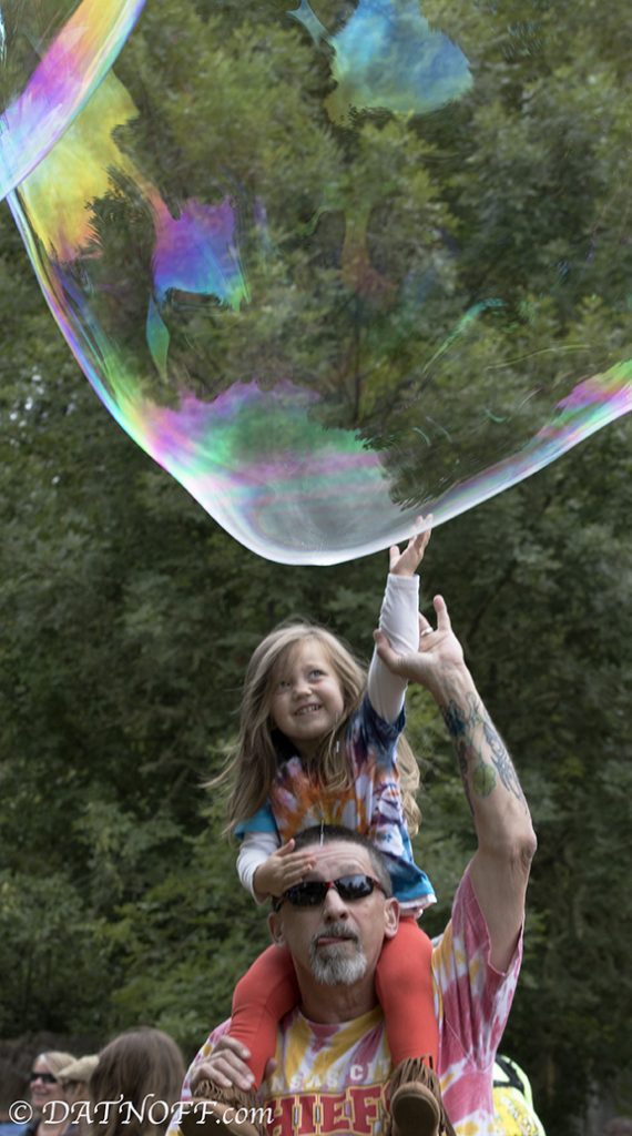 Child reaching for huge bubble at Oregon Country Fair