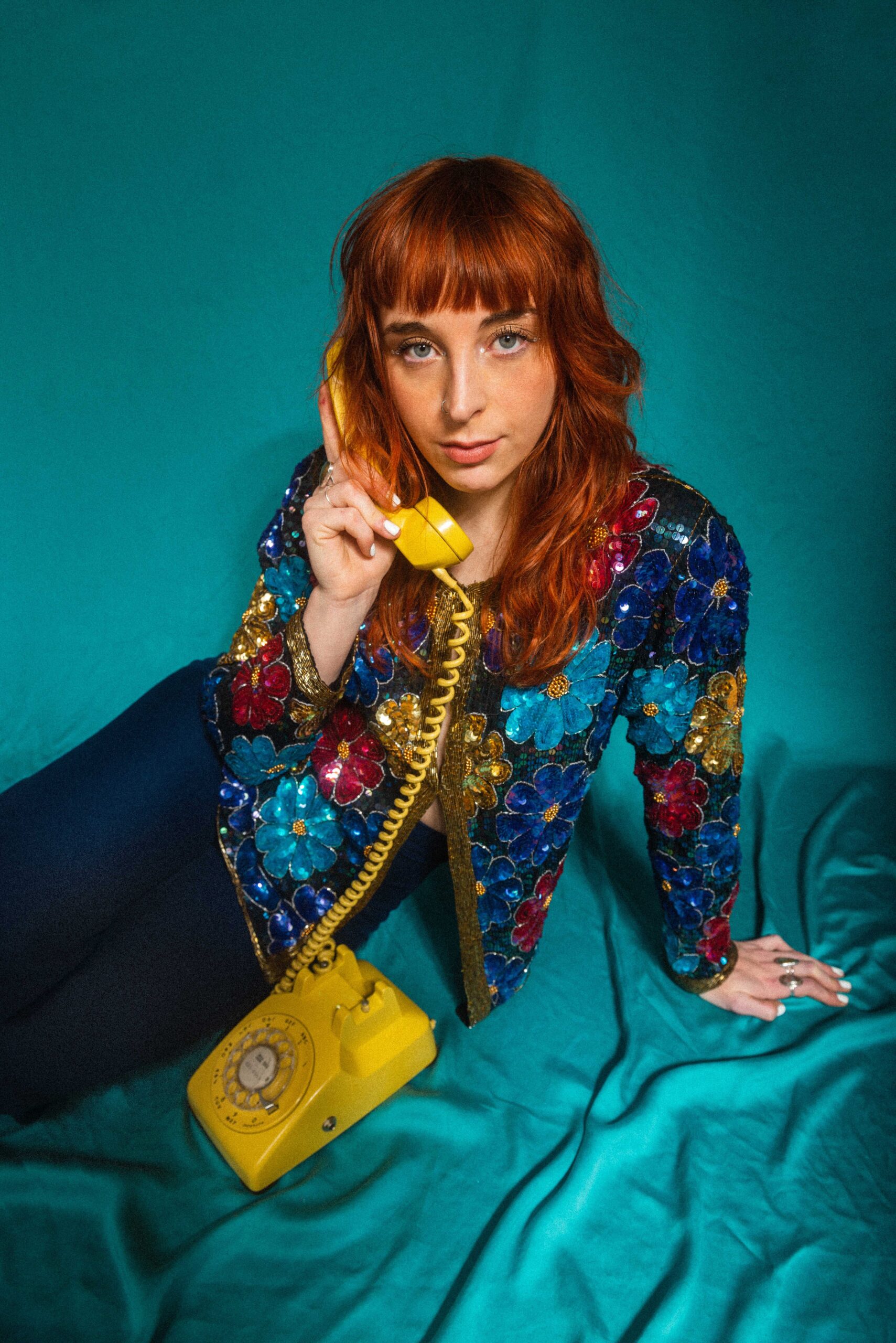 Photo of Kendall Lujan, on a rotary phone, looking into the camera.
