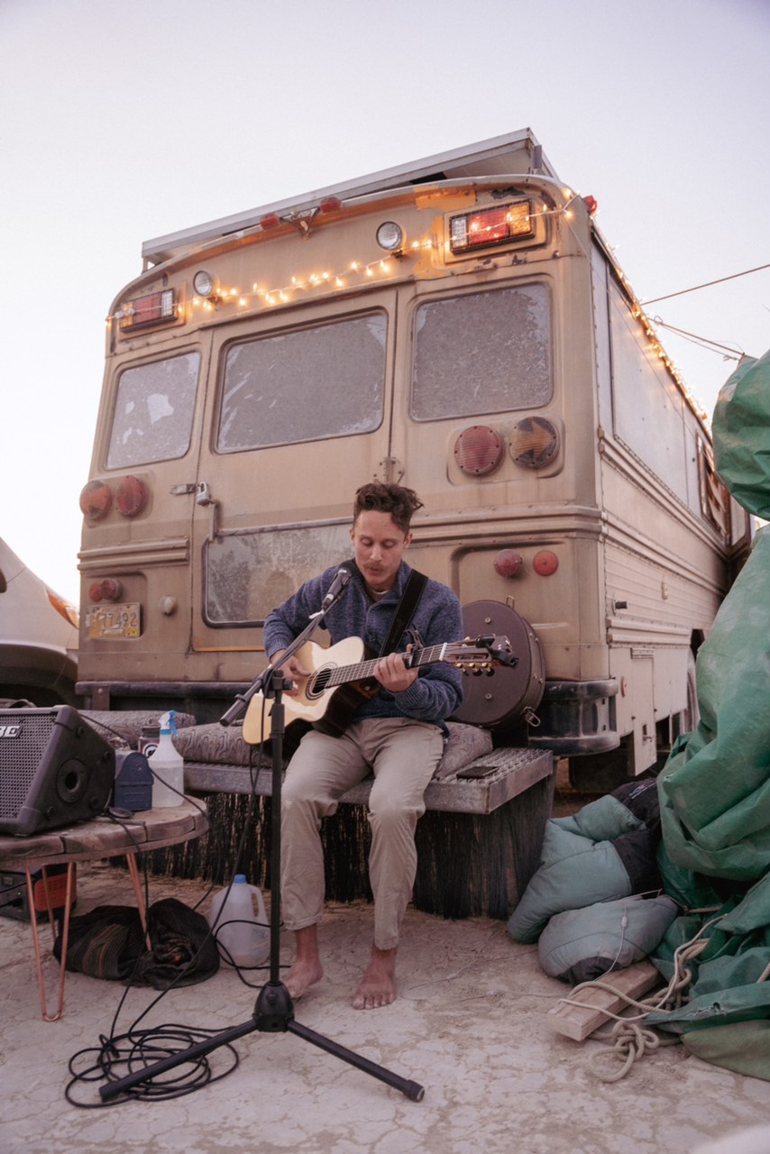 Rich Rollins plays guitar on the back of a bus.