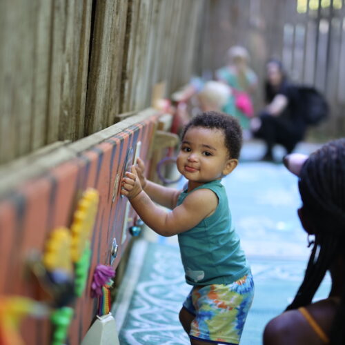 A beautiful toddler is playing and smiling in an age appropriate play area
